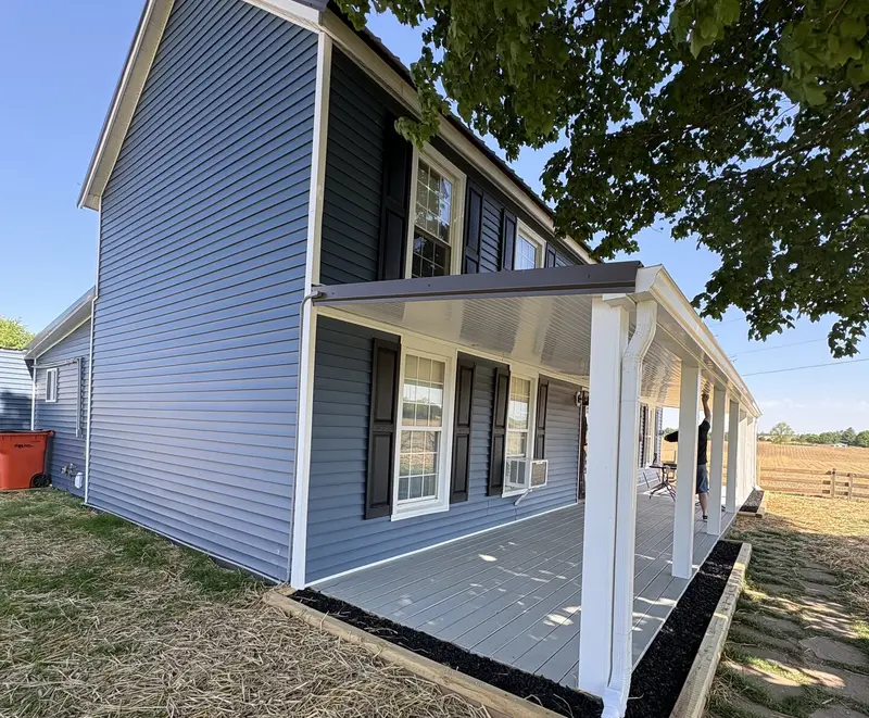 Two-story farmhouse in Brandenburg, KY with new navy vinyl siding and a covered porch, completed by RenovateX LLC
